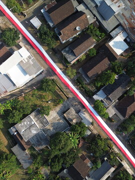 Aerial view of a long red and white Indonesian flag stretched across a residential neighborhood in Wonosari, East Java, Indonesia.