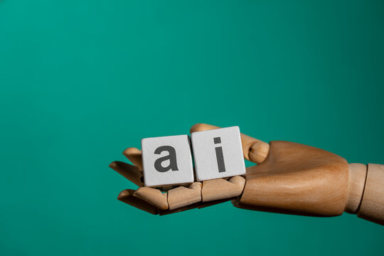 Wooden robot hand holding cubes with AI text abbreviation, close up. Mannequin hand holding white blocks with letters spelling AI. Artificial intelligence tech industry innovative digital solution