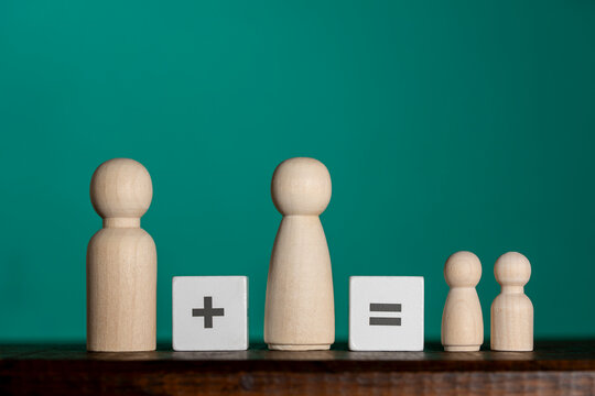 Wooden peg dolls and math signs family planning concept. Family equation concept with wooden peg figures representing parents and children separated by plus and equals signs on green background
