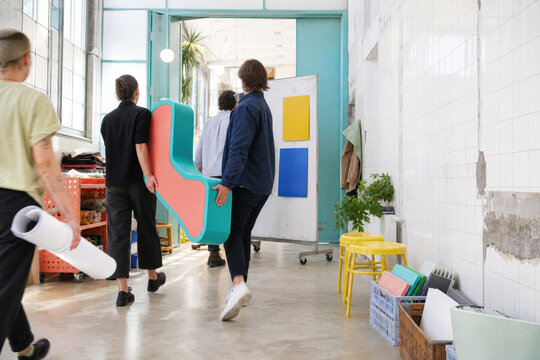 Prototype Handoff in Bright Office Corridor with Creative Team and Copy Space
