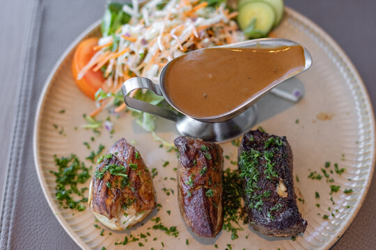 Gourmet meat trio of grilled chicken, pork, and beef served with rich mushroom sauce and side salad on plate - top view
