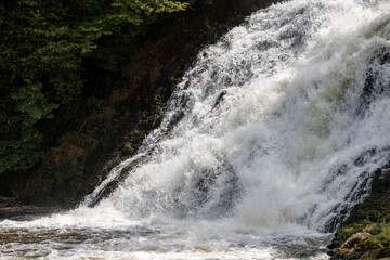 Obraz premium Powerful rushing water cascading down rocky slopes surrounded by forest at Les Cascades de Coo - Belgium
