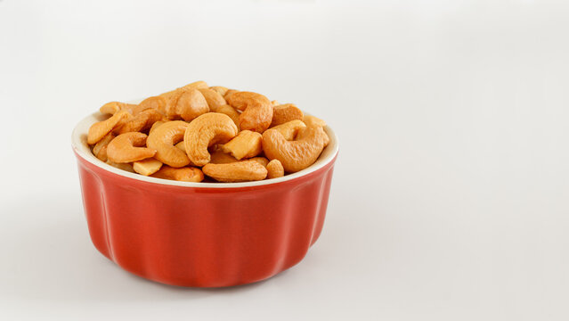 Roasted cashew nuts served in a small red ceramic bowl with copy space.