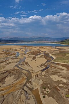 Aerial view of Twin Lakes showing the intricate patterns of the receding shoreline and sediment deposits under a bright blue sky in Twin Lakes, Colorado, United States.