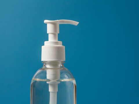 Clear plastic soap dispenser pump bottle with liquid on blue gradient background for hygiene products