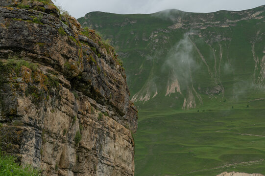 Rolling green slopes rise beneath heavy clouds and soft mist