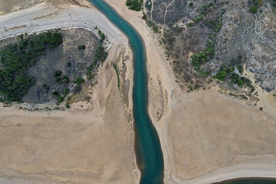 Aerial view of the turquoise waters of Twin Lakes flowing through the arid, sandy landscape with sparse vegetation and rugged terrain in Twin Lakes, Colorado, United States.