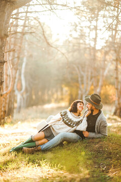A loving couple spends time together in a sunny forest. A young woman and man, dressed stylishly, stroll and relax on an autumn day at sunset. The concept of love, relaxation, and enjoyment.