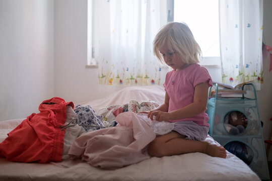 Little Girl Sorting Clean Laundry on the Bed
