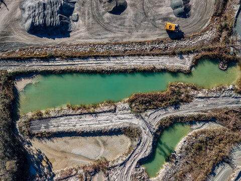 Aerial view of Holcim Australia - Petrie Quarry featuring turquoise water ponds, industrial earthworks, and heavy machinery in Kurwongbah, Queensland, Australia.
