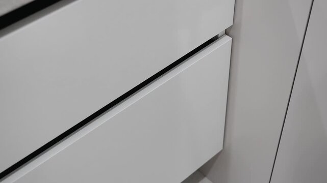 closing of a white drawer with a pull system. built-in black L-shaped handle profile. modern innovative repair, technologies