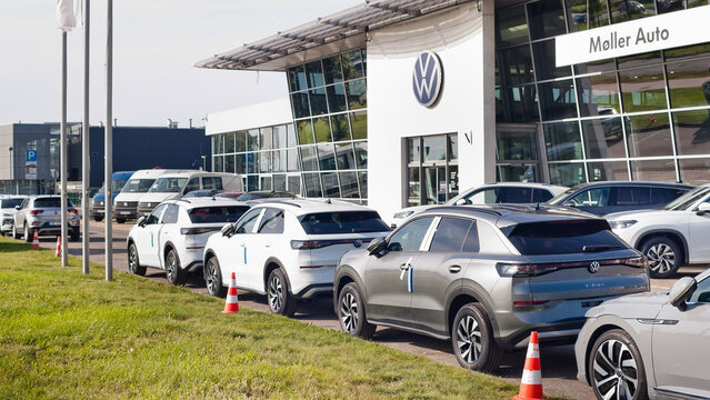 Riga, Latvia, August 14, 2026: New Volkswagen cars on the street near the auto center, in the background is the building of the auto center and a billboard with the VW logo