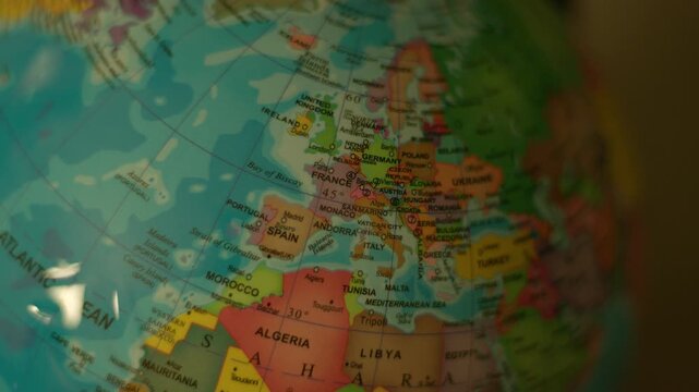 Globe spins slowly, showing detailed continents and oceans. European nations are clearly labeled, with vibrant colors. Soft lighting highlights textures and geography in close-up
