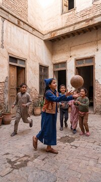 Moroccan girl in blue djellaba catching ball with children in old riad courtyard
