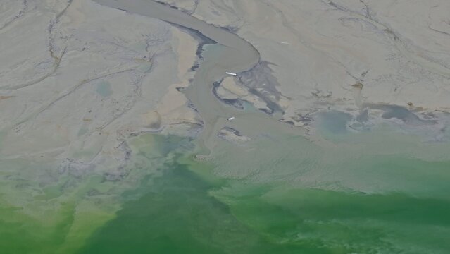 Aerial view of Mayflower Tailings Pond with its distinctive grey sediment and green water in the mountainous landscape of Summit County, Colorado, United States.