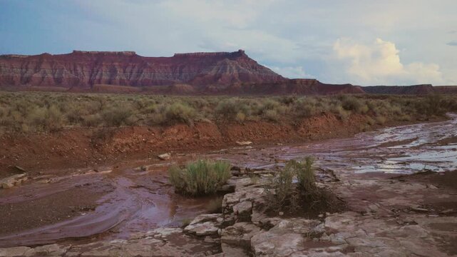 Water trickles down a wash in the desert below Gooseberry Mesa in Southern Utah USA as the flood from a heavy summer monsoon storm passes and the clouds began dissipating in the evening light.  