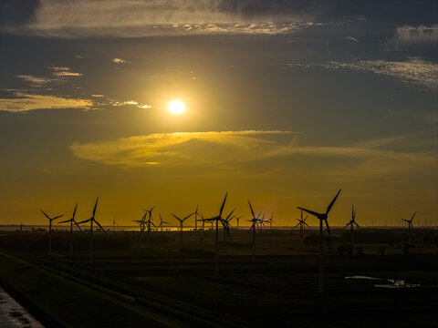 Aerial view of wind turbines in a field at sunset with golden light and silhouettes in Emden, Niedersachsen, Germany.
