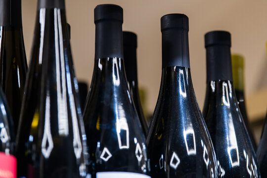 Closeup of dark glass wine bottles with cork closures. Beverage packaging and alcohol industry concept with reflective containers arranged