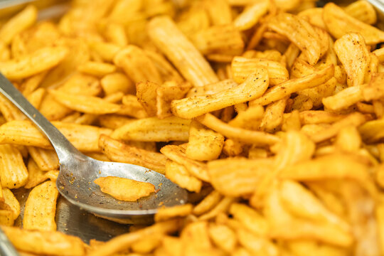 Close up of crispy seasoned potato fries with serving spoon. Golden fried snack texture for food menu, restaurant, catering,