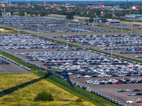 Aerial view of the vast Volkswagenwerk Emden car storage lot filled with thousands of new vehicles parked in neat rows at the industrial facility in Emden, Niedersachsen, Germany.