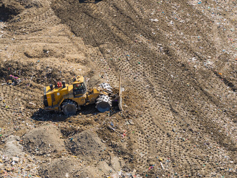 Compactor Works on Piles of Waste at a Local Landfill Site During the Bright Daytime