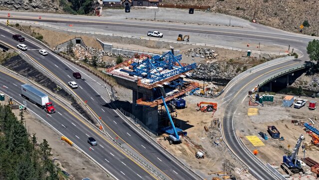 Aerial view of bridge pier construction featuring a blue steel structure and heavy machinery alongside highway traffic in Floyd Hill, Colorado, United States.