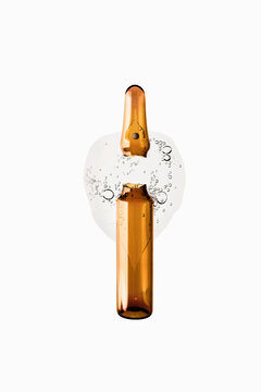 Broken amber ampule releasing serum with bubbles on white background