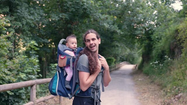Happy father carrying daughter in backpack exploring nature