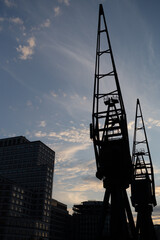 Fototapeta premium Silhouetted Industrial Cranes Against a Blue Evening Sky in Urban Setting