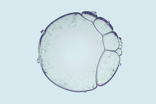 Macro shot of clean liquid gel texture with structure of fluid round spheres and micro bubbles on light blue background.