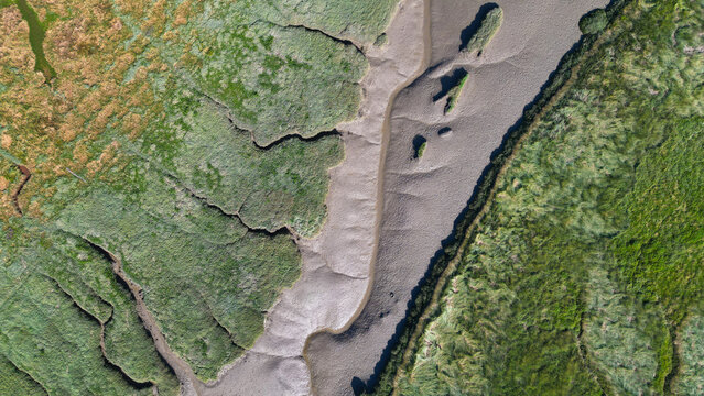 Aerial view of the tidal marshlands and winding mudflats of the estuary in Billiers, Brittany, France.