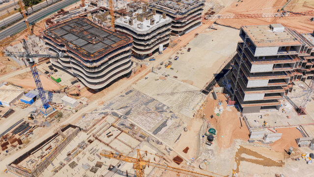 Aerial view of modern buildings under construction with multiple cranes and concrete structures at a large development site in Athens, Greece.