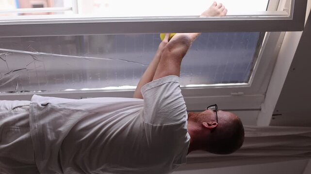 Man Installing Solar Window Film for Heat Protection at Home. 4k