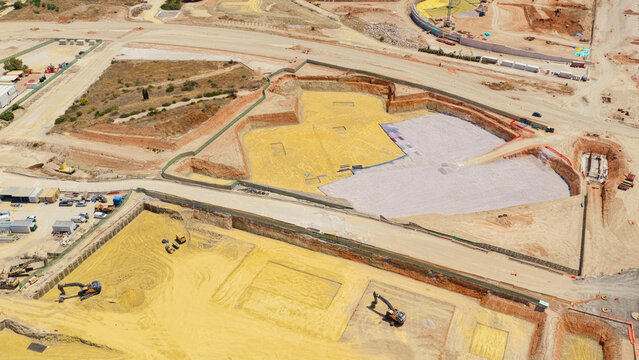Aerial view of a large construction site featuring deep excavation pits, heavy excavators, and piles of earth in Athens, Greece.