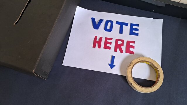 Vote here sign with blue and red letters near ballot box