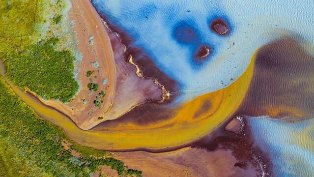 Aerial view of Thjorsarver river delta with vibrant mineral deposits and glacial water patterns in Iceland.