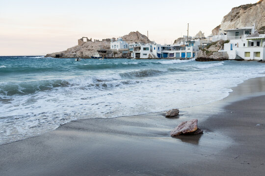 Scenic sunset at Firopotamos beach on Milos island, Greece, with a traditional whitewashed houses and church along the coast.