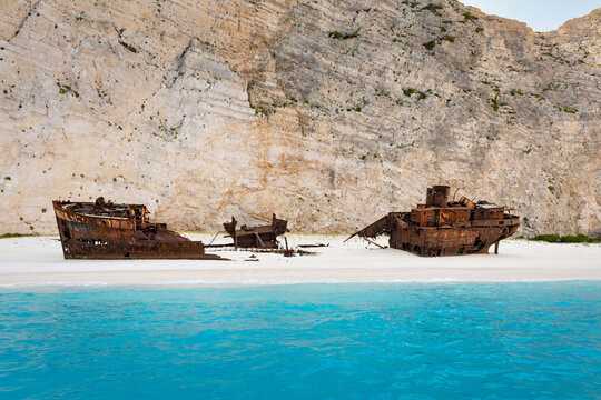 Sea-level view of Navagio Beach in Zakynthos, Greece, with the remains of the MV Panagiotis shipwreck surrounded by towering white cliffs and the blue waters of the Ionian Sea.