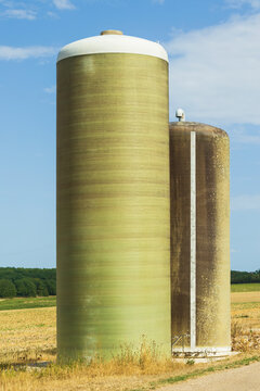 Silos agricoles en bordure d&rsquo;un champ de c&eacute;r&eacute;ales en Bourgogne, sous un ciel bleu marqu&eacute; par une forte chaleur estivale.
