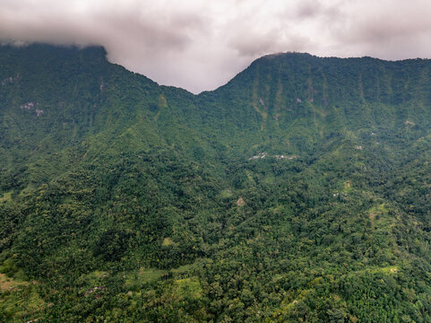 Aerial view of Amed landscape featuring lush green mountains, dense tropical vegetation, and cloudy skies in Abang, Bali, Indonesia.
