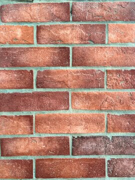 Full frame horizontal shot of a classic red brick wall texture with light grey mortar lines.