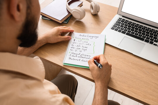 Man learning arabic language with notebook and laptop, online education and remote study