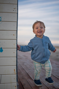 Happy Toddler Boy Leaning Against a Wooden Beach Hut