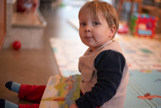 A 23-month-old toddler boy holding a children's book and looking directly at the camera