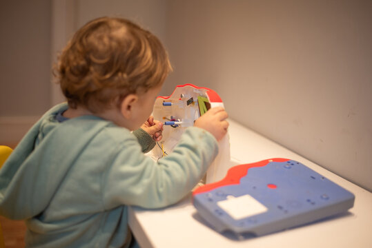 A curious toddler examining the internal wires of a broken cash register with the cover open