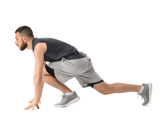 Fototapeta premium Young man in athletic wear in a starting block position, fitness and determination concept, isolated on white background