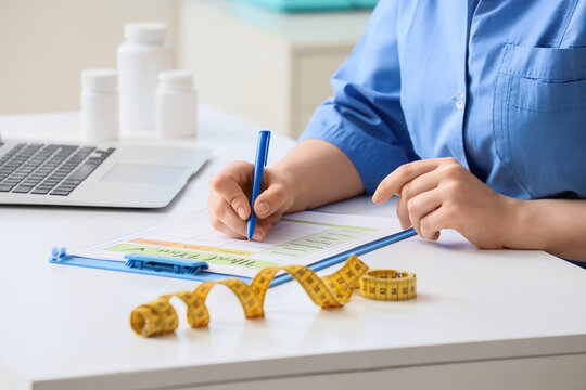 Nutritionist or doctor writing a meal plan for a patient, healthy lifestyle and diet concept, weight loss and wellness program