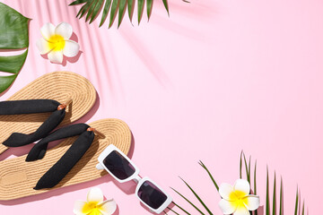 Fototapeta premium Summer composition with beach accessories, plumeria flowers and tropical leaves on pink background