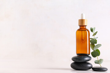 Spa stones and bottle of eucalyptus essential oil on light background, closeup © Pixel-Shot