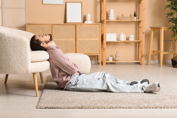 Tired young man sleeping on floor at home